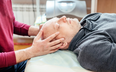 A man lying on his back, looking very relaxed as he receives Chiropractic cranial adjustments
